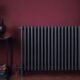 A black radiator against a maroon wall endorsing energy efficient home solutions