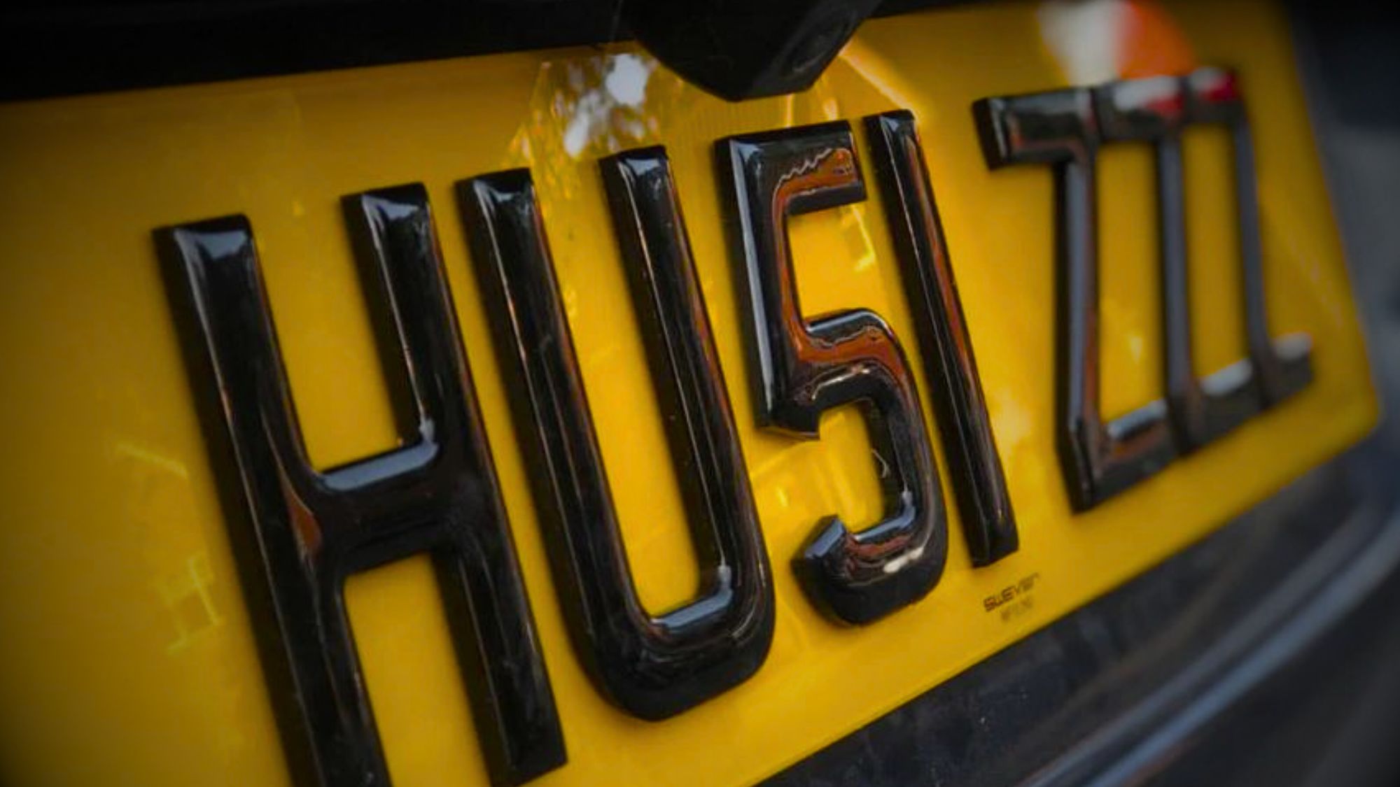 A close-up of the word HU5I ZZZ on a 4D license plates