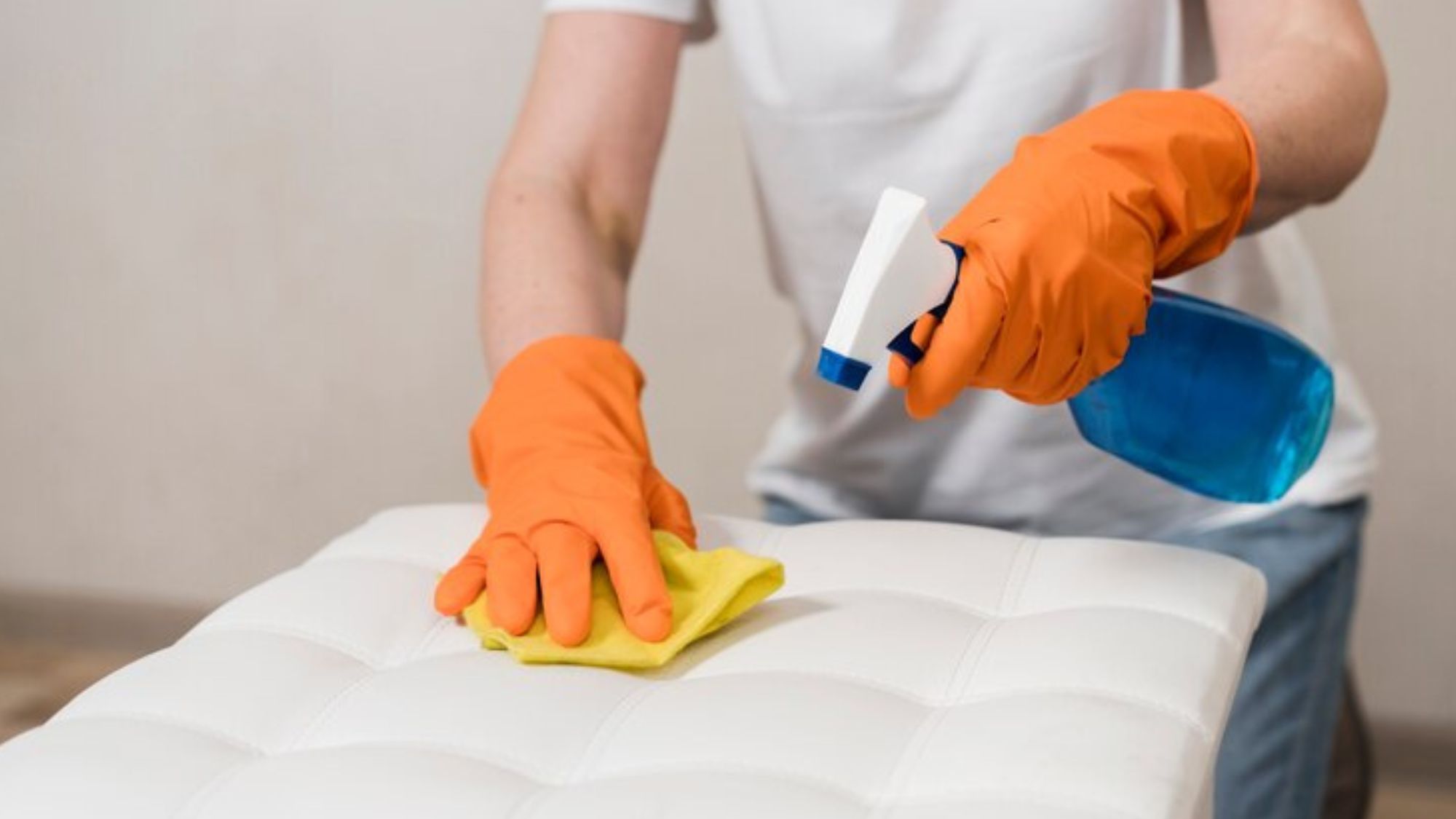A woman cleaning spots of a bedding with a detergent spray in hand