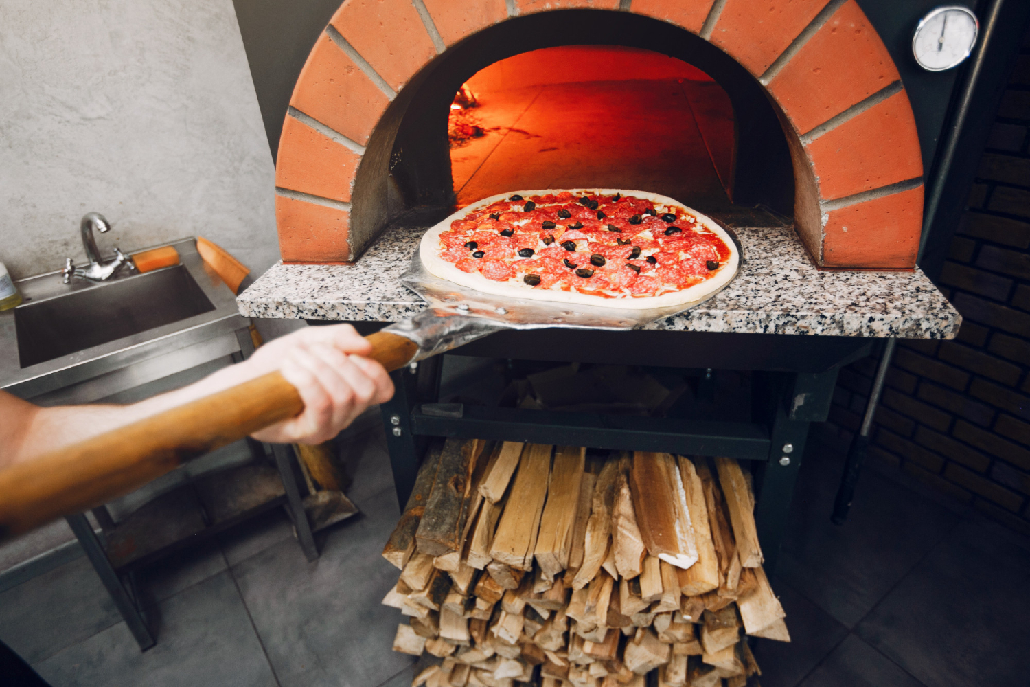 Chef putting pizza in pizza ovens